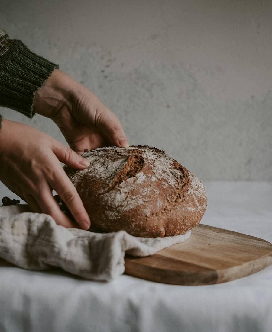 Baker shaping sourdough dough on a floured bench
